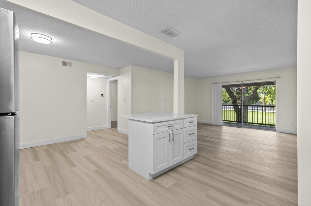 A white kitchen with a wooden floor and a refrigerator on the left.