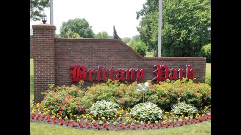a brick wall with a red sign and flowers in front of it