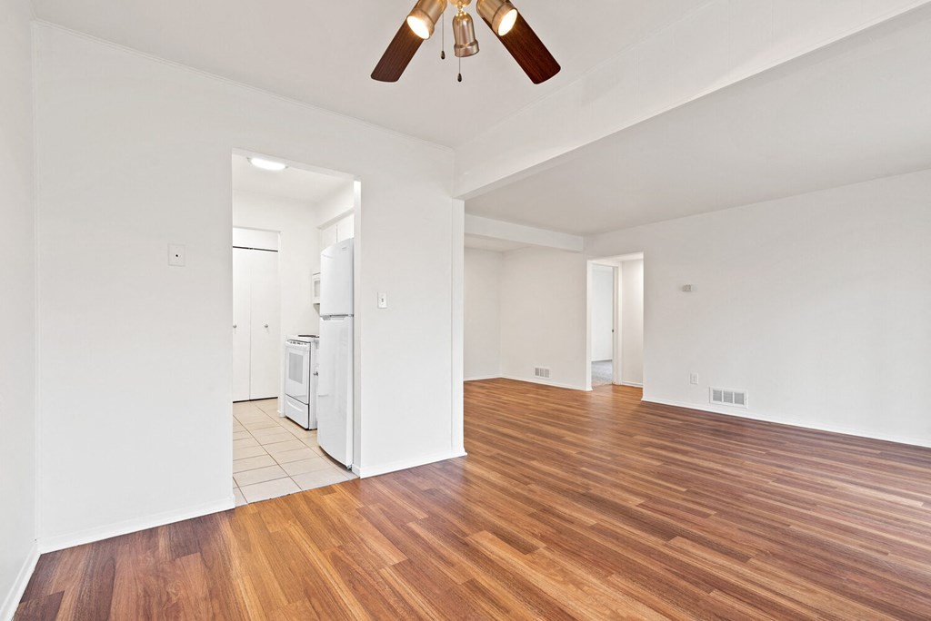an empty living room with hardwood flooring and a ceiling fan