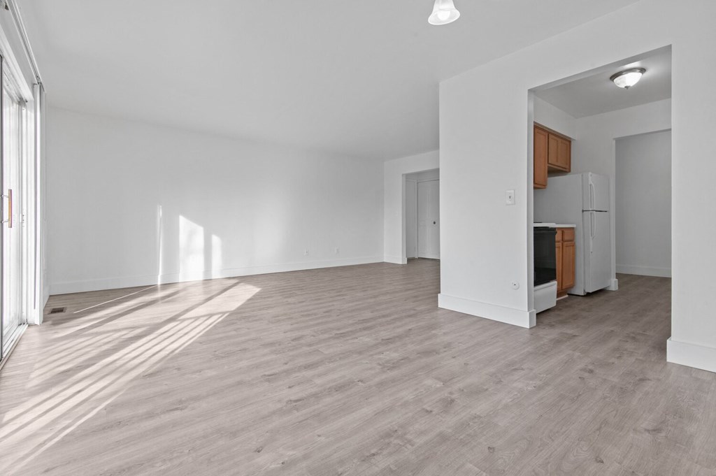 the living room and kitchen in a new home with white walls and wood flooring