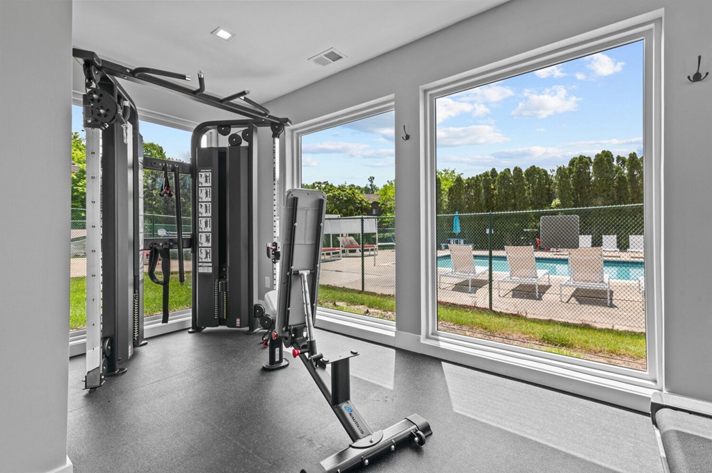 a home gym with windows and a view of a pool