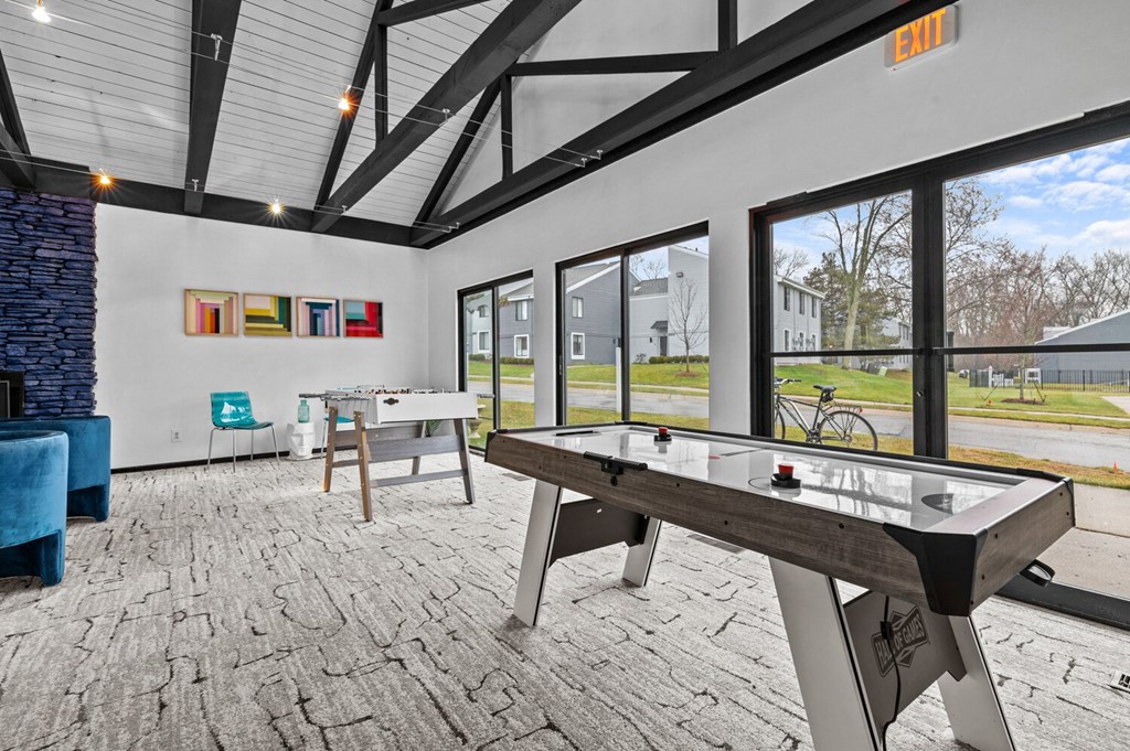 a games room with two ping pong tables and large windows