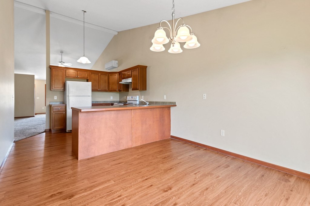 an empty living room and kitchen with wood flooring