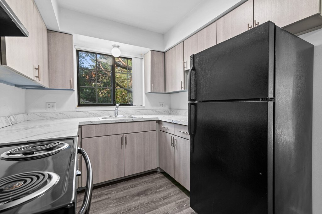 a kitchen with wooden cabinets and a black refrigerator