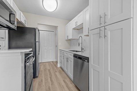 A kitchen with white cabinets and a black refrigerator.