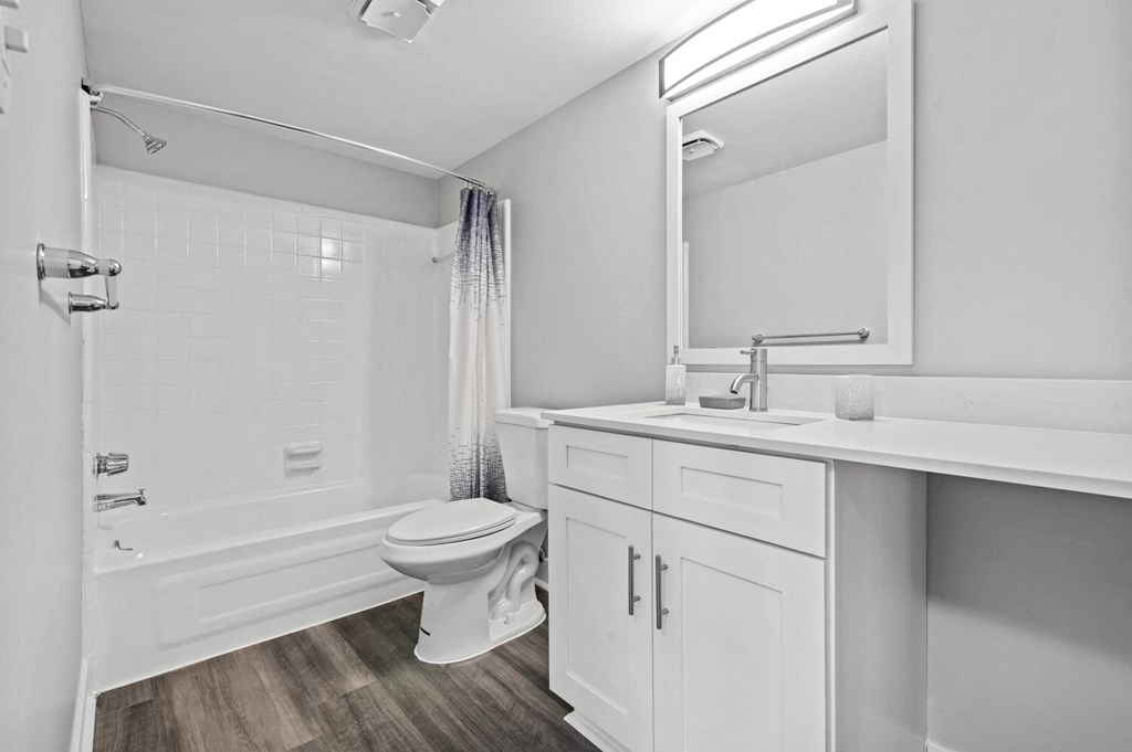 a white bathroom with a shower toilet and sink at Sunnymede Apartments - Troy, MI, Troy