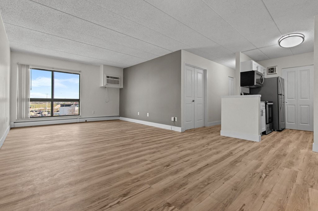 an empty living room with wood flooring and a window