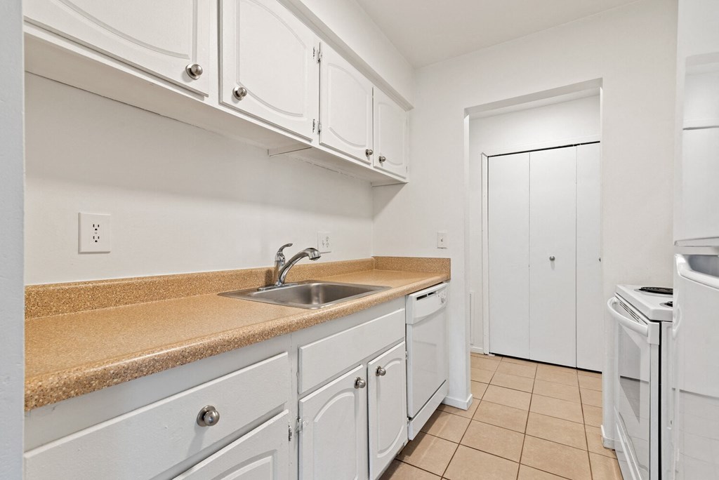 a kitchen with white cabinets and a sink and a white refrigerator