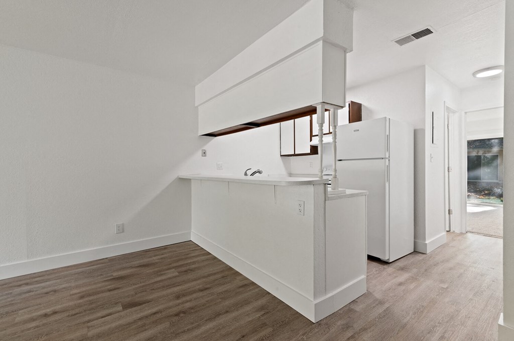 an empty kitchen with white cabinets and a white refrigerator