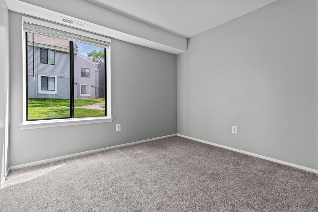 A room with a window showing a house across the street.