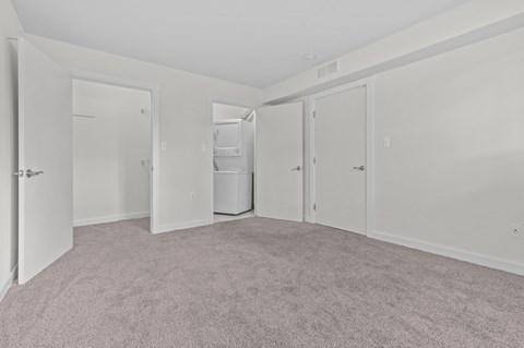 the living room of an apartment with white walls and carpet