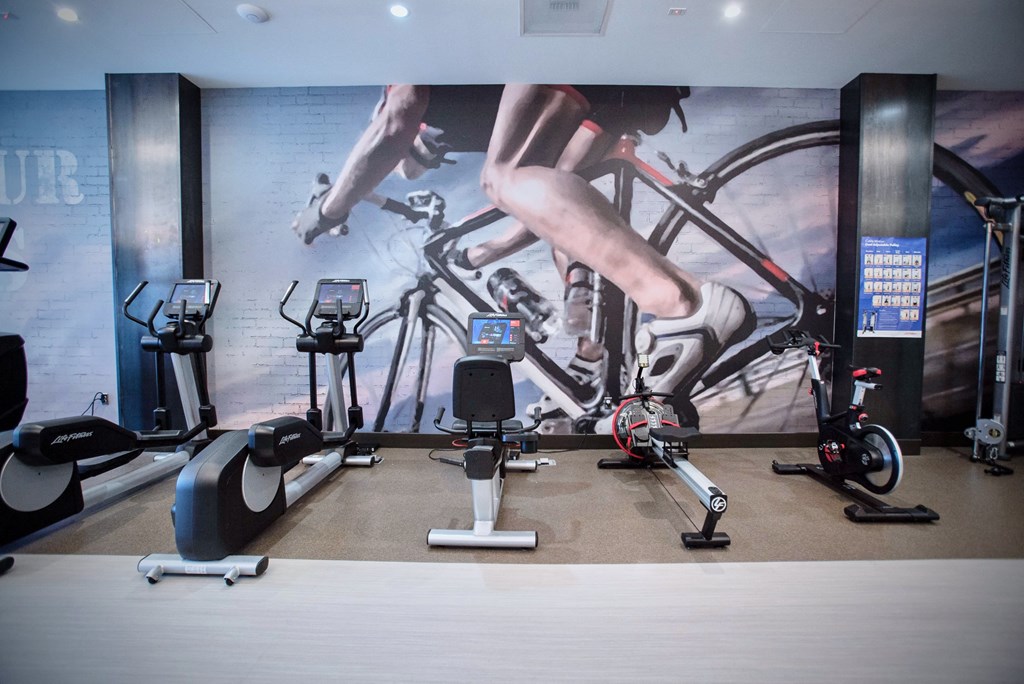 a gym with exercise equipment and a wall mural of people on bikes