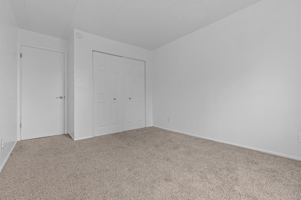 a bedroom with white walls and carpet and a white door