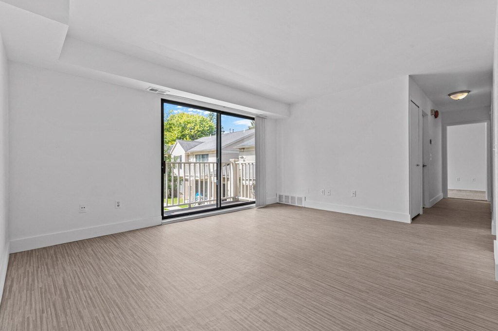 an empty living room with a sliding glass door leading to a balcony