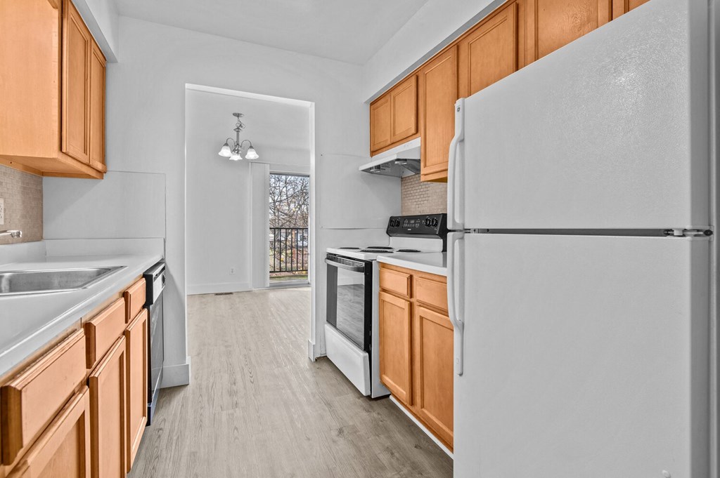 an empty kitchen with white appliances and wooden cabinets