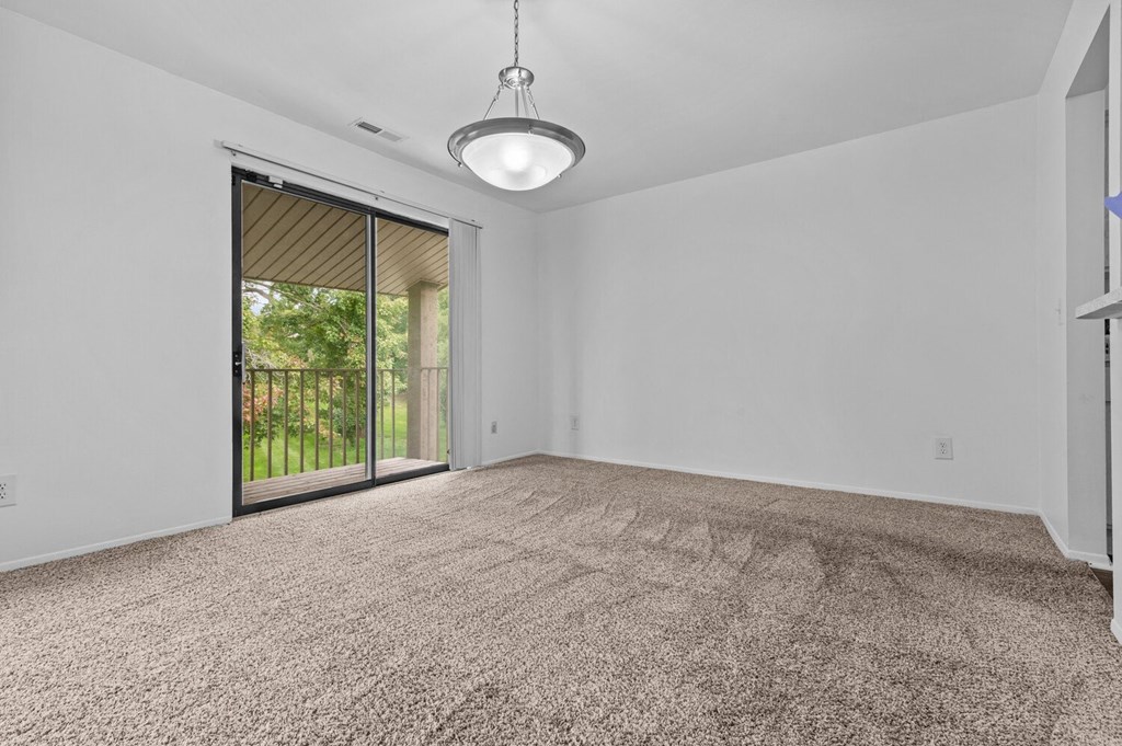 an empty living room with a sliding glass door to a patio at Edge At Farmington Hills - Farmington Hills, MI, Farmington Hills, Michigan