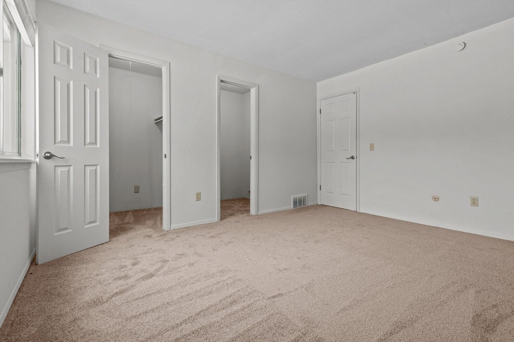 the living room of an apartment with carpet and white doors