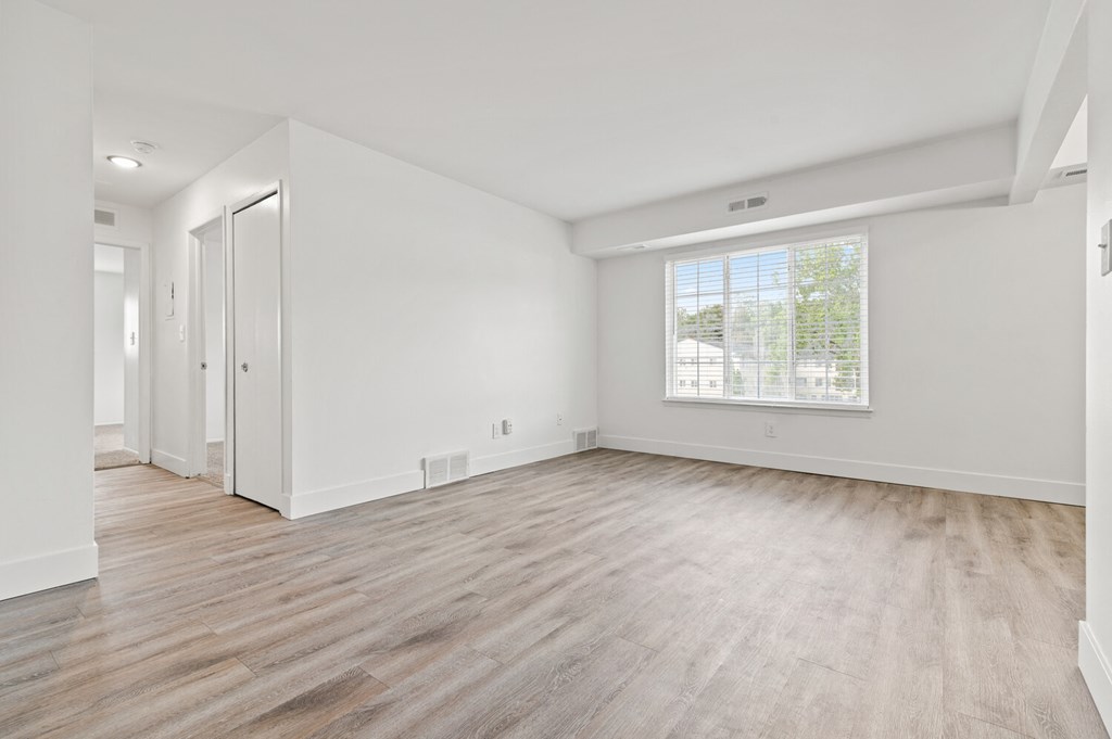 an empty living room with white walls and a window