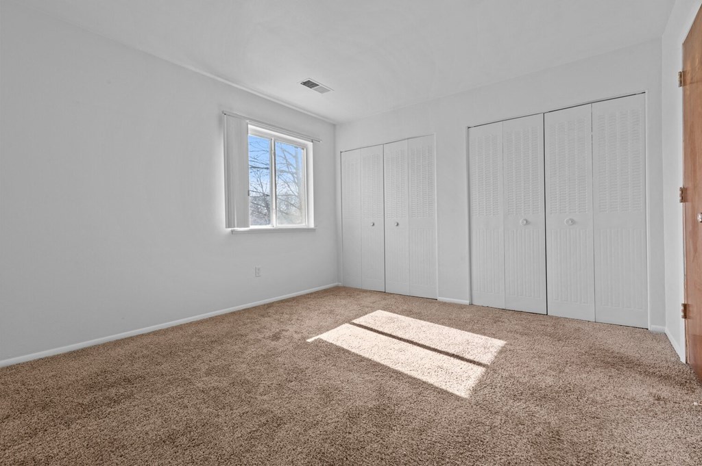 a room with carpet and white walls and a window