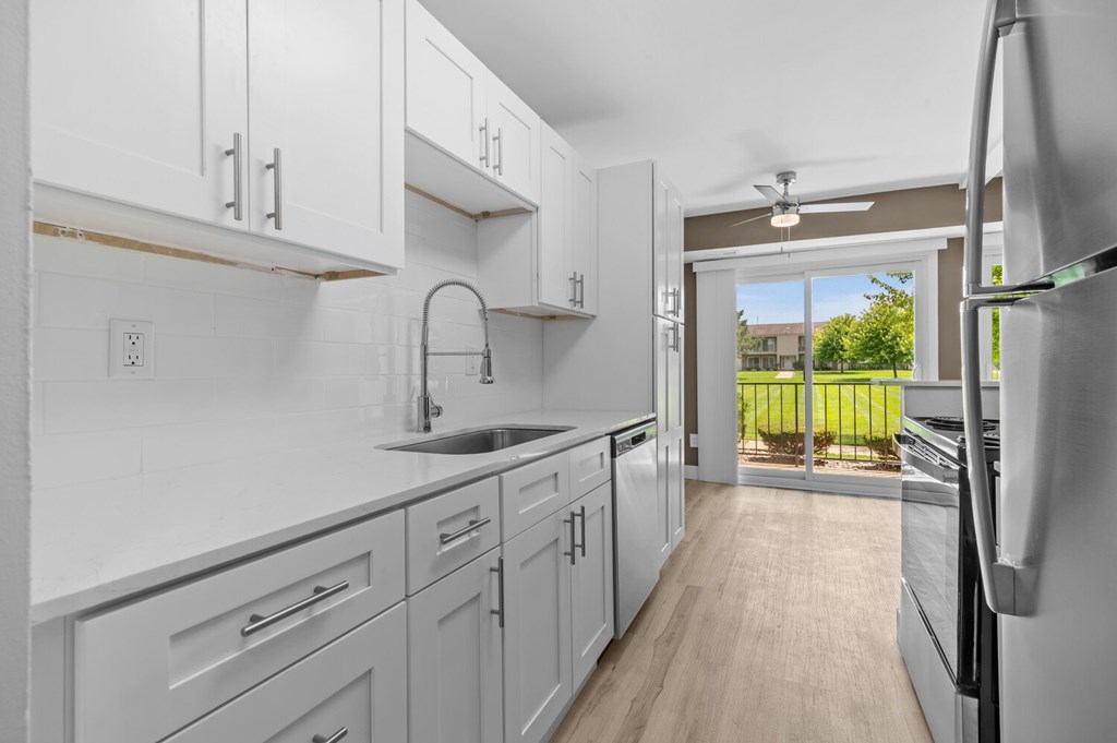 a white kitchen with white cabinets and a sliding glass door