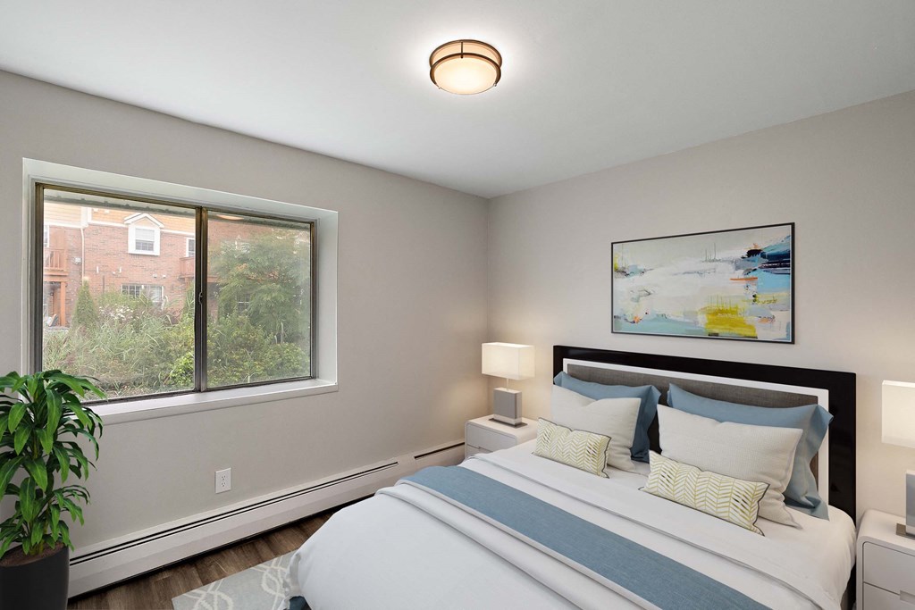 the master bedroom has a large window and a bed with blue and white pillows