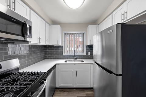 a kitchen with white cabinets and stainless steel appliances and a window