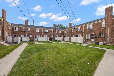 an image of a large brick building with a yard in front
