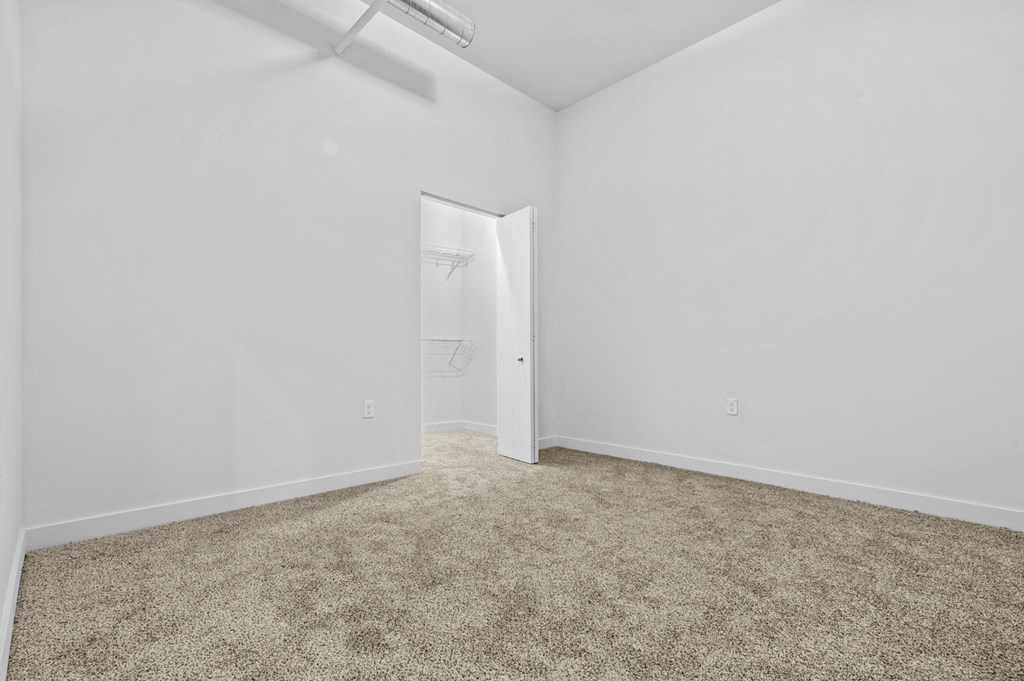a bedroom with white walls and carpet