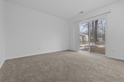 an empty living room with a sliding glass door to a yard