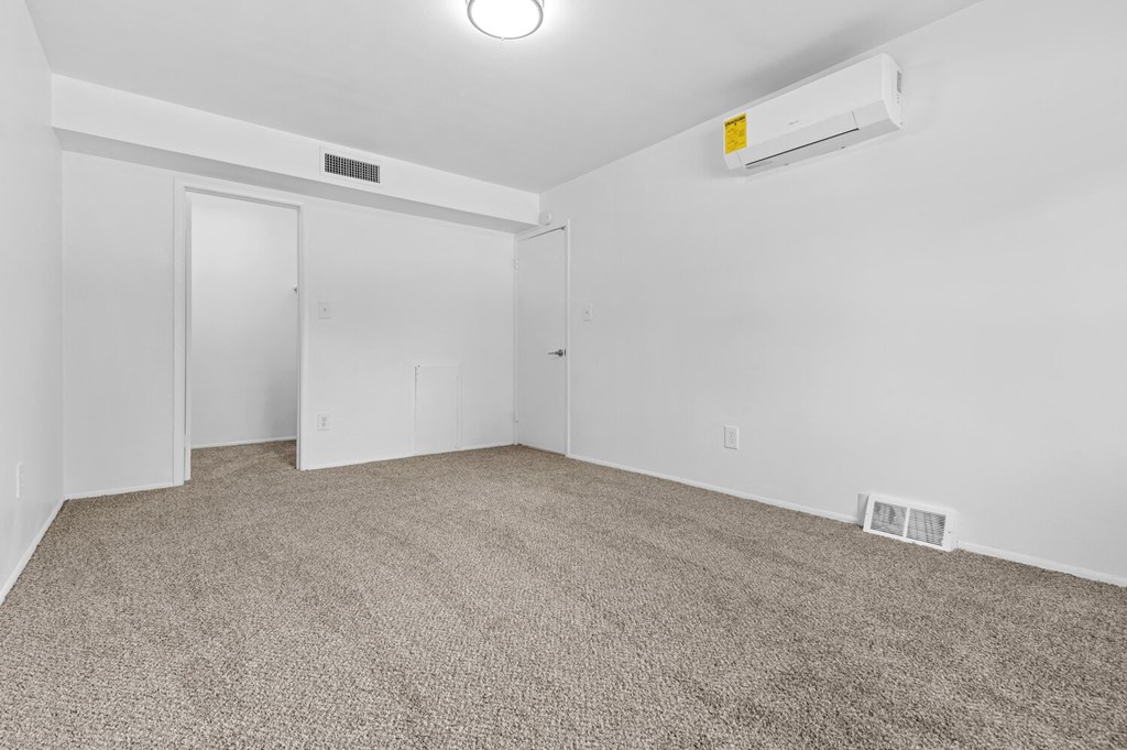 a bedroom with white walls and carpet