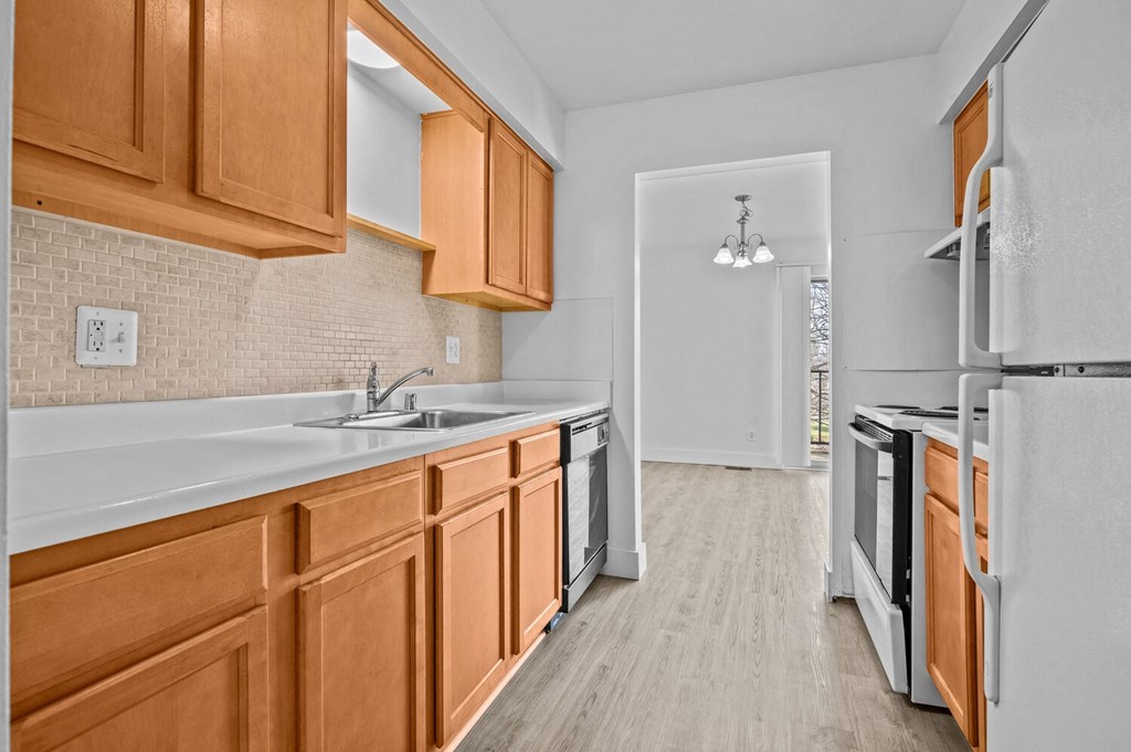an empty kitchen with wood cabinets and white appliances