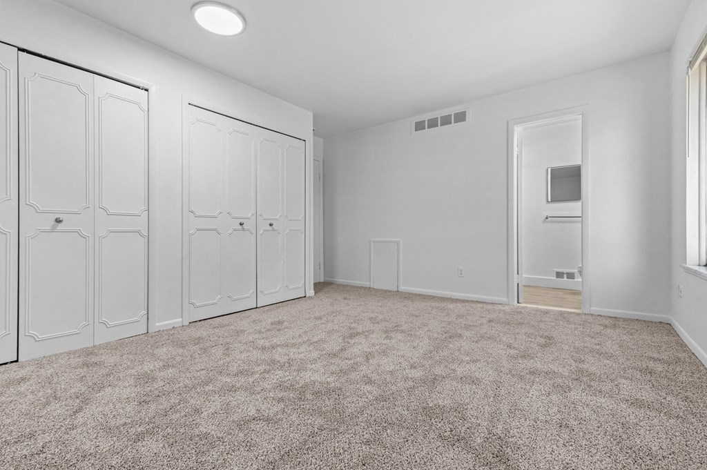 an empty room with white closets and carpeting
