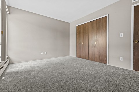 a bedroom with grey carpet and a wooden door