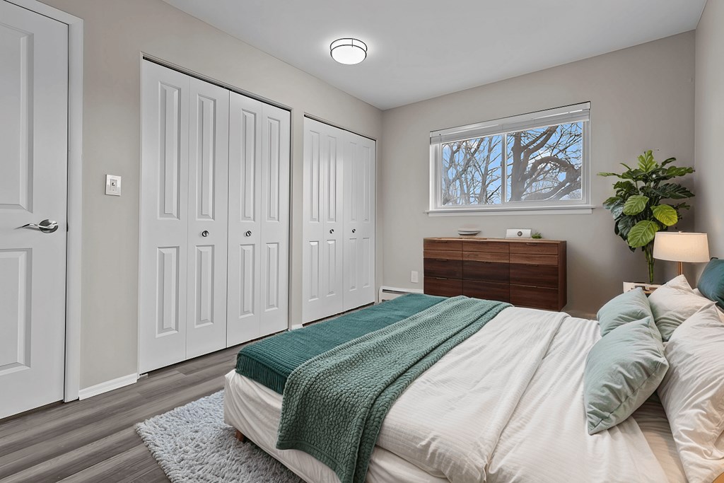 A bedroom with a bed, a dresser, and a window.