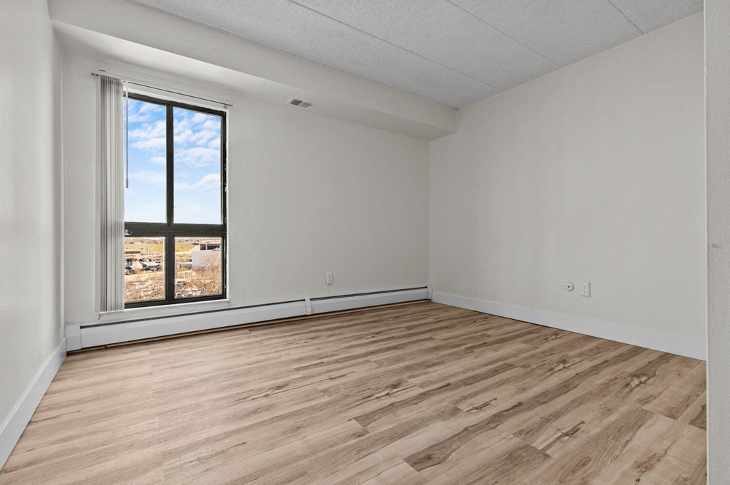 an empty living room with wood floors and a window