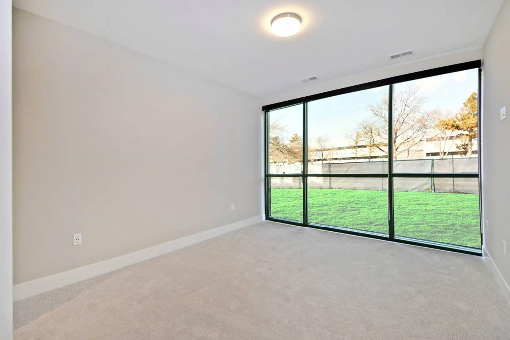 A room with a large window overlooking a grassy area.