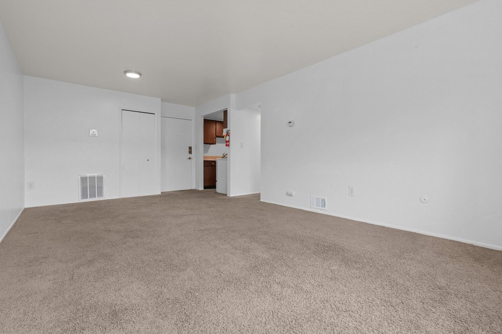 an empty living room with carpet and white walls