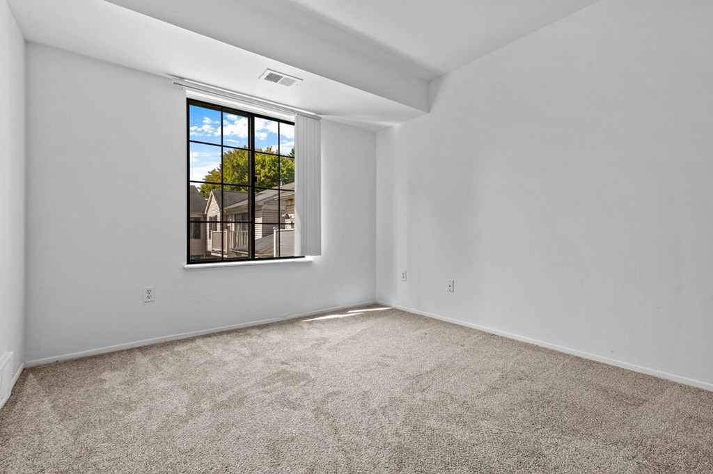 a bedroom with a large window and carpet
