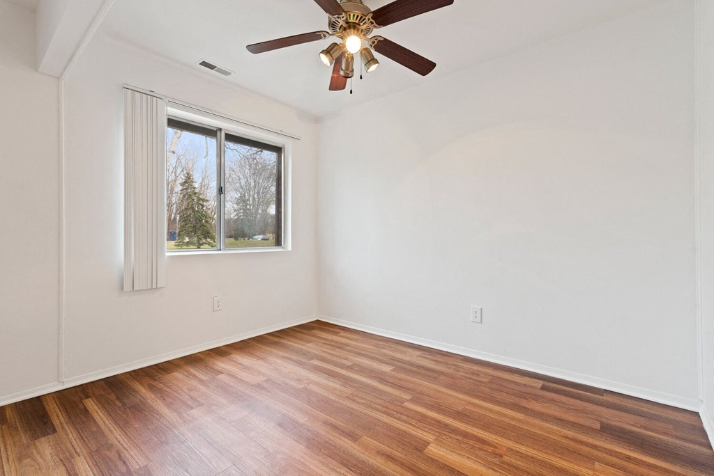 an empty living room with wood floors and a ceiling fan