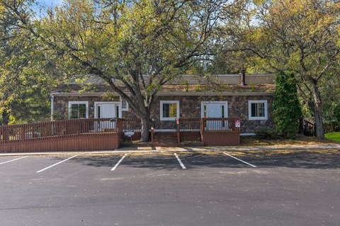 the front of a house with a parking lot and trees