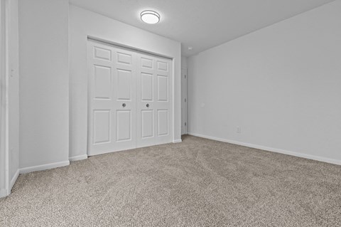 an empty bedroom with white doors and carpeting