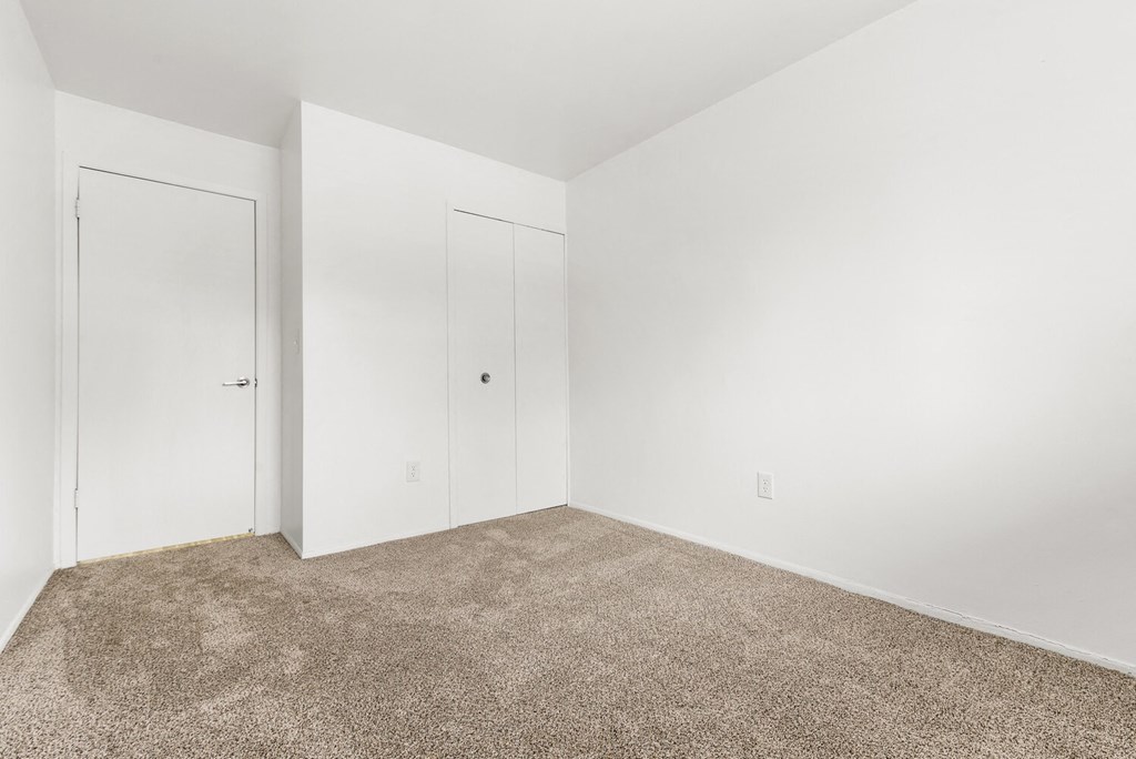 a room with carpet and white walls and doors
