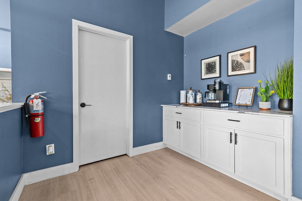 a hallway with blue walls and white cabinets and a fire extinguisher