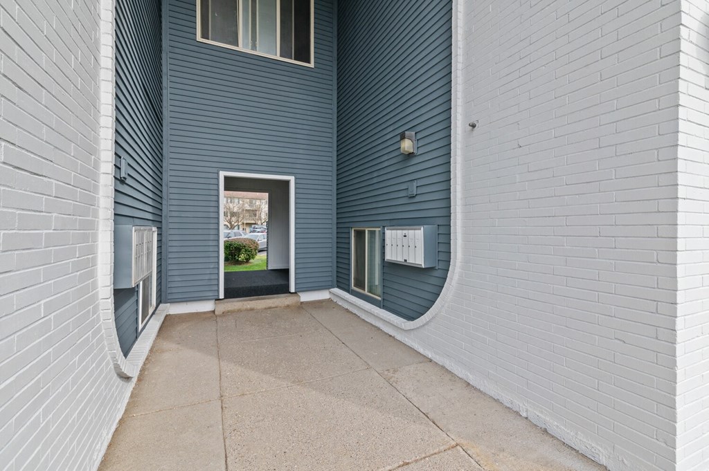 a long hallway with a door to a building with blue and white walls