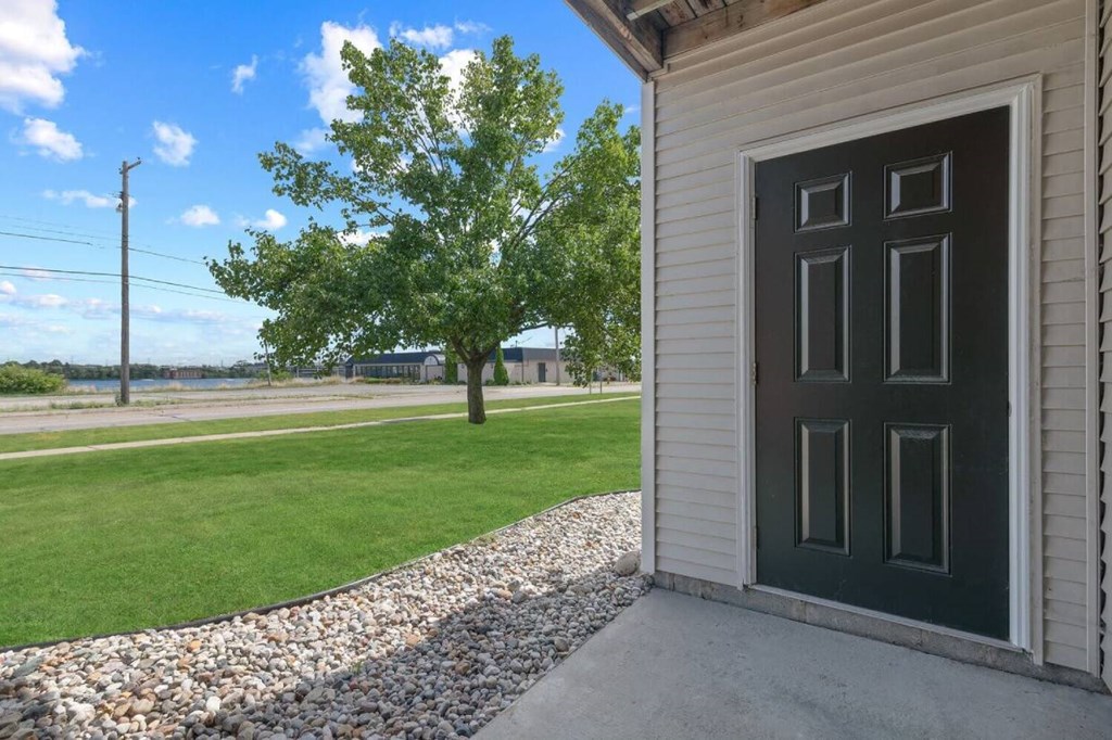 a door on the side of a building with a grassy area and trees in the background