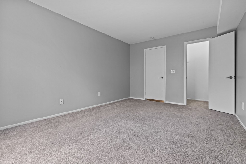 A room with three doors and carpeted floor.