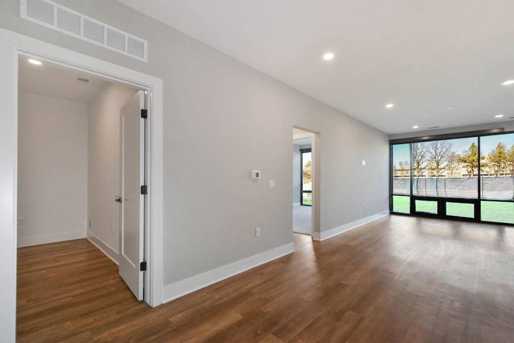 A room with wooden floors and a large window overlooking a fenced area.