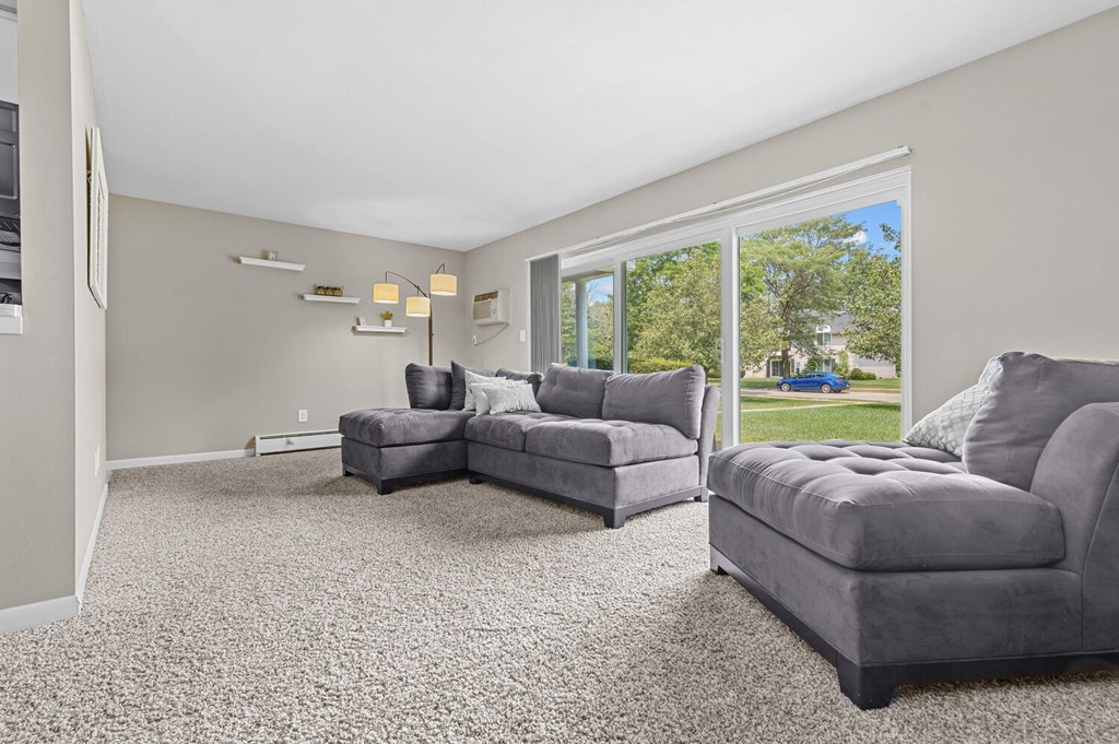 a living room with two couches and a large window at Apple Ridge Apartments - Livonia, MI, Livonia, Michigan