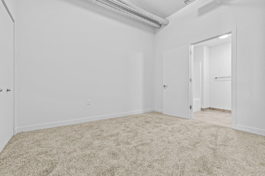 a bedroom with white walls and carpet