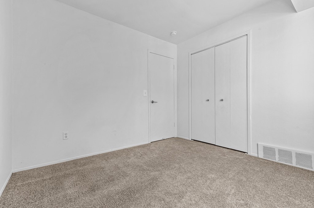 a bedroom with white walls and carpet